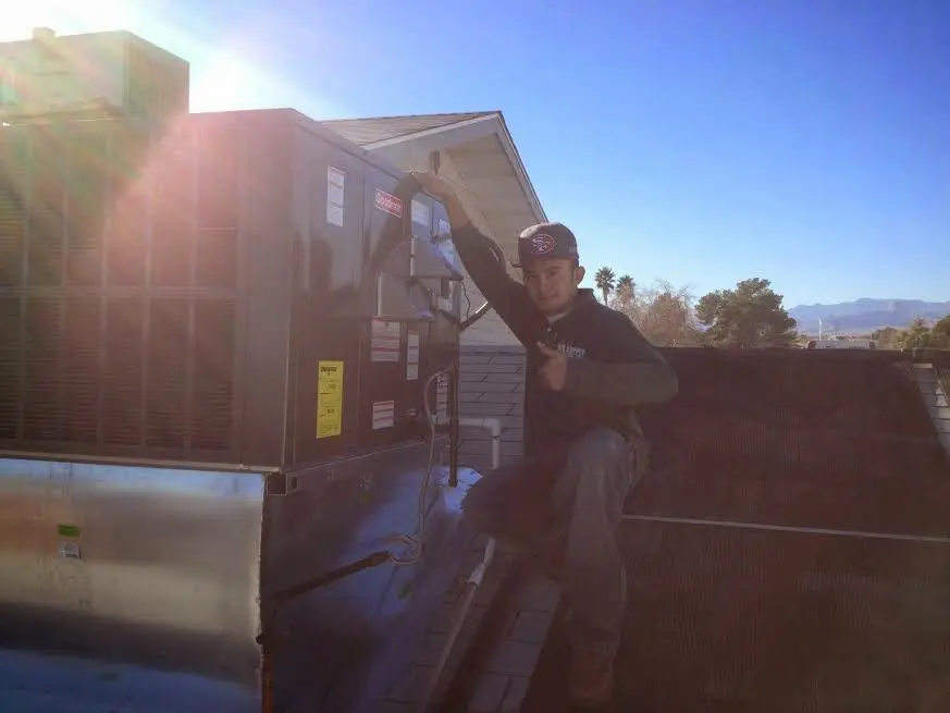 HVAC technician performing Heat Pump Repair on a rooftop unit in Troy